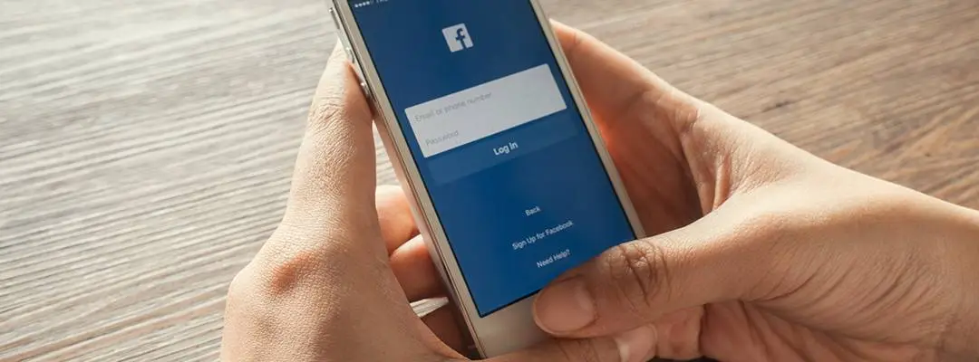 Persona utilizando su celular para abrir la aplicación de Facebook

